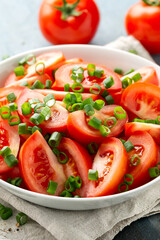 Tomato salad with spring onion and herbs in white bowl. Healthy summer food
