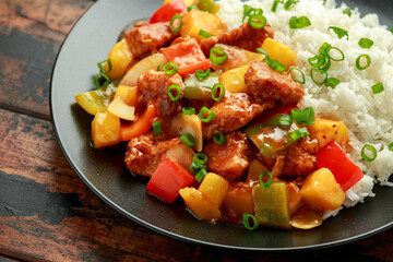 Pineapple and Chicken in sweet and sour sauce with bell pepper, rice and spring onion in black plate
