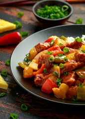 Pineapple and Chicken in sweet and sour sauce with bell pepper, rice and spring onion in black plate