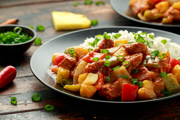 Pineapple and Chicken in sweet and sour sauce with bell pepper, rice and spring onion in black plate