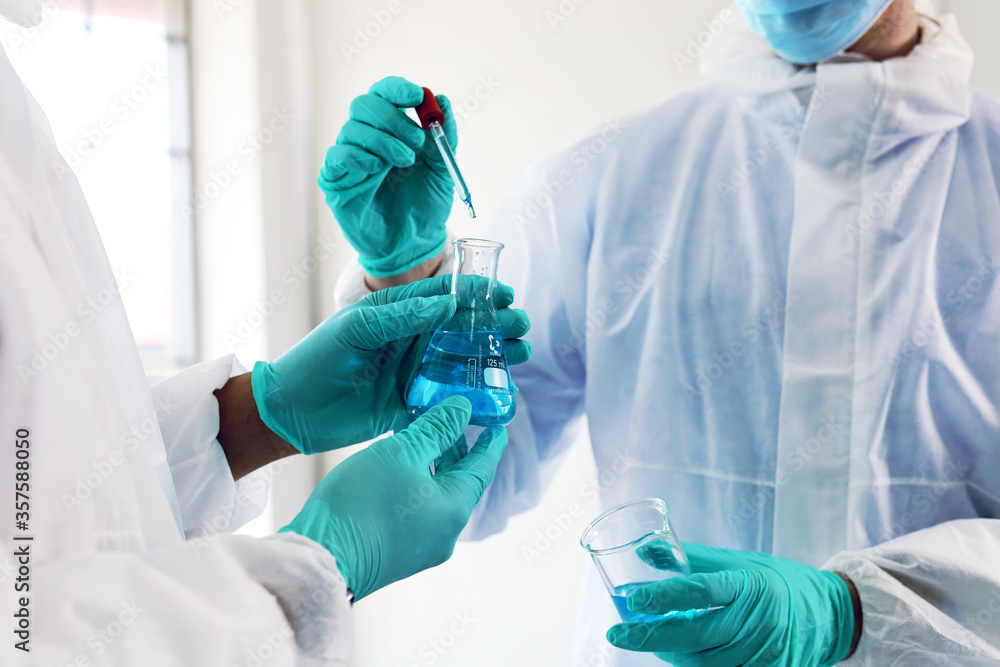 Wall mural two young men scientist using a microscope for looking solution in corona virus laboratory in a chem