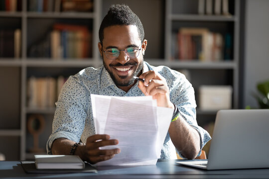 African student guy sitting at desk holding papers printed tasks perform test prepares for entrance exams enjoy process of study. Teacher checking assignment homework, company lawyer paperwork concept