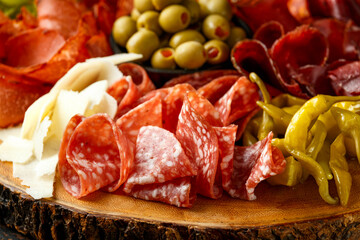 Dry cured fermented beef and pork meat cocktail selection with salami, chorizo, cheese, olives and grapes served on wooden board