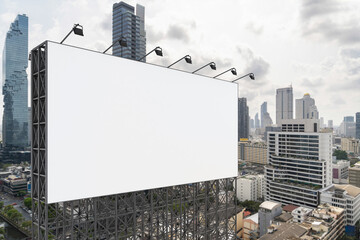 Obraz premium Blank white road billboard with Bangkok cityscape background at day time. Street advertising poster, mock up, 3D rendering. Side view. The concept of marketing communication to promote or sell idea.