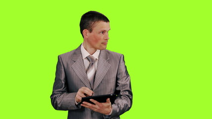 Young businessman in suit using a tablet on green screen background, Chroma key