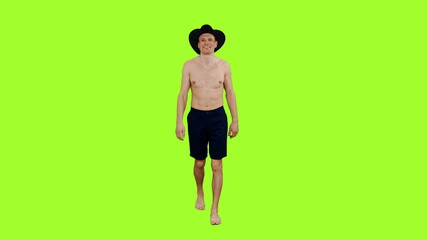 Smiling young man with naked torso walks in black cowboy hat and shorts on green screen background...