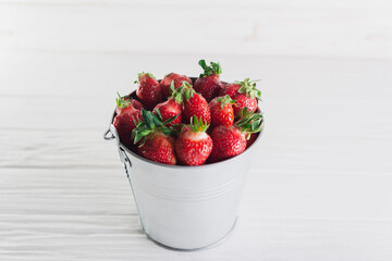 Juicy fresh strawberries in a metal bucket on a white background