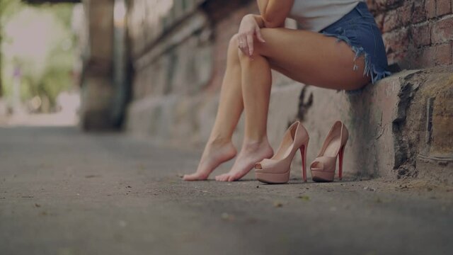 bare feet of a tired girl on a city street