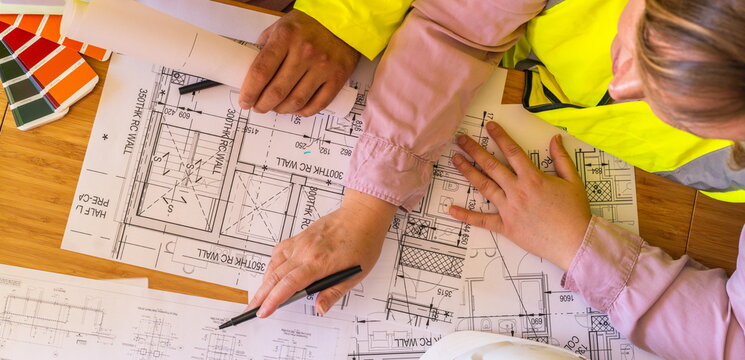 Two architects working on plans. Architect holding a smartphone on construction site. young construction worker is using mobile phone on site. Construction worker with building plans and cellphone. 