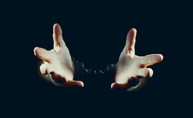 hands and handcuffs, in dark background.          