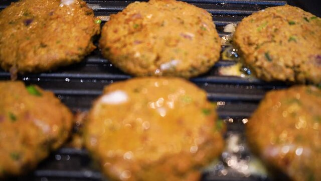 Shallow depth of feild shot mince meat mutton patties keema roasting on a pan with oil bubbling out as they get charred