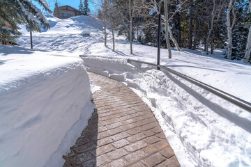 Stone brick pathway with metal handrails amid deep layer of snow in winter