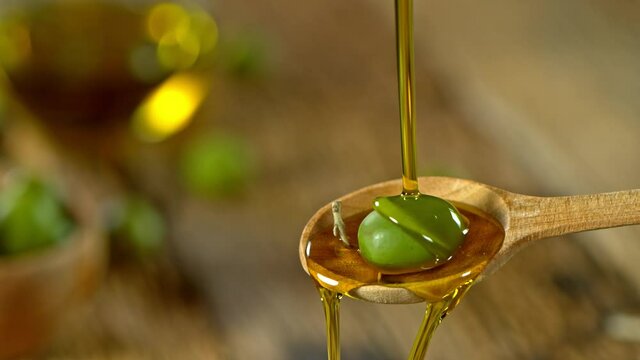 Super Slow Motion Shot of Pouring Fresh Olive Oil on Olive at 1000 fps.