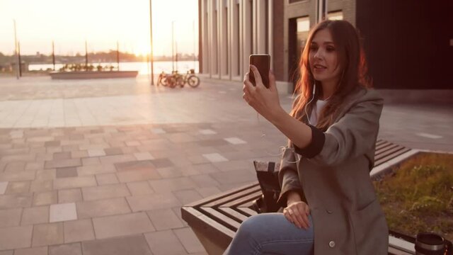 Young attractive business woman sitting outdoor on the bench. Sunset light.