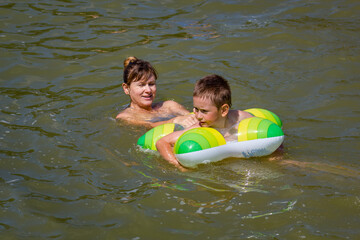 Fototapeta premium Boy with mother swimming with inflatable ring in the lake