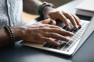 Close up image african male hands typing on laptop keyboard. Businessman answer on client e-mail,...