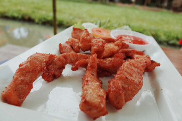 Fried pork in white dish with chilli sauce, restaurant in garden