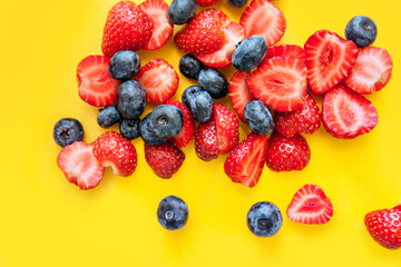 Mixed fresh berries: blueberry and strawberry on a yellow background