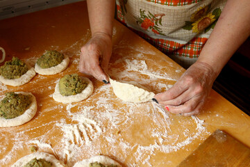 Color photo of female hands making stuffed pies. Appetizing cooking. Work in the kitchen.