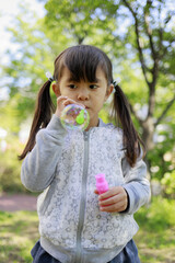 緑の中でシャボン玉で遊ぶ幼児(5歳児)