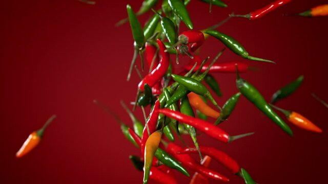 Super Slow Motion Shot of Mixed Chilli Side Colision on Dark Red Background at 1000fps.