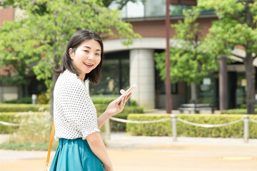 Fototapeta premium スマホを片手に笑顔の女性