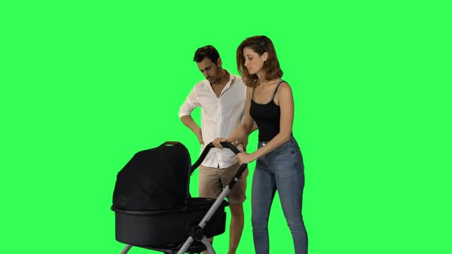 Frustrated parents pushing a stroller with a crying baby over green screen
