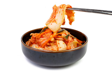 Kimchi cabbage in a bowl with chopsticks on white background, top view.