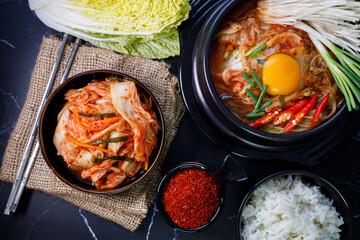 Eating kimchi cabbage and rice in a black bowl with chopsticks.