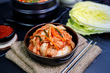 Eating kimchi cabbage and rice in a black bowl with chopsticks.