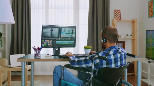 Handicapped video editor in wheelchair working from home wearing headphones. Handicapped invalid paralysed freelancer, immobilized entrepreneur working from home, ilness and disability