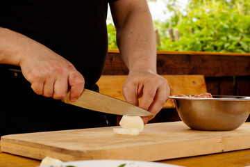 the chef cuts the onion to fry on the Board. hands with a knife in the frame.