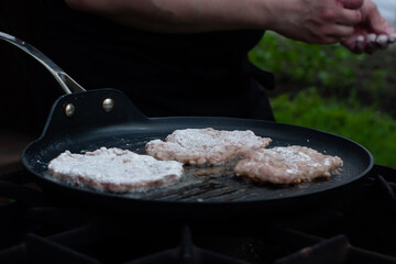 the cook roasts the cutlets in a pan over the fire. food on the grill in nature. picnic.
