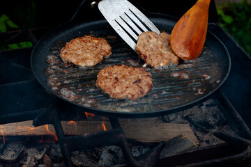 the cook roasts the cutlets in a pan over the fire. food on the grill in nature. picnic.