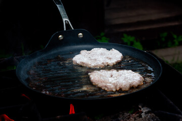 the cook roasts the cutlets in a pan over the fire. food on the grill in nature. picnic.