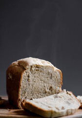 A loaf of bread and a slice of bread on the wooden cutting board