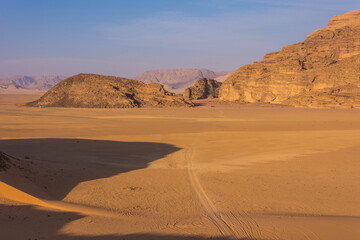 Fototapeta na wymiar Desert with rocky mountains and wheel tracks in the sand