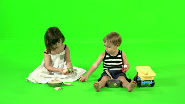 Cooking with kitchen toys by two cute kids over green screen.