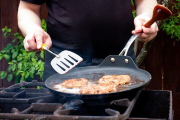 the cook roasts the cutlets in a pan over the fire. food on the grill in nature. picnic.