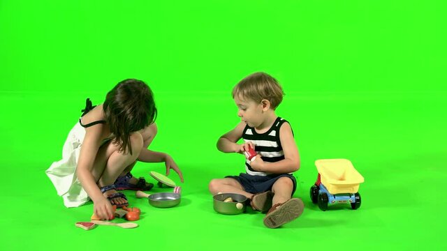 Two cute kids playing with kitchen toys over green screen.