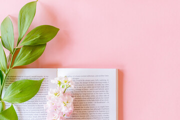 Top view of open book and Pink Matthiola incana or Mathilda Lavender with ruscus twig on pastel pink background with copy space.