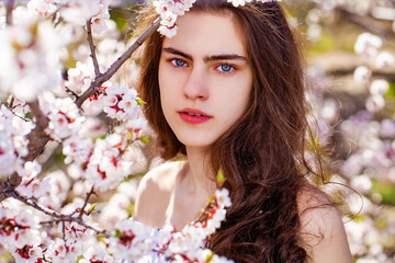 Fototapeta premium Pretty teen girl are posing in garden near blossom cherry tree with white flowers