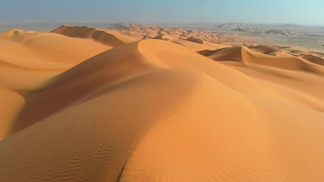 Rub' al Khali, aka Empty Quarter desert, Arabian Peninsula. Flying over curve shaped sand dunes during hot summer weather. Aerial shot, 4K