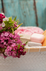 Spa towels and soaps in a basket with flowers