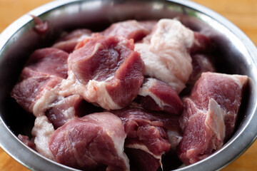 pork shoulder cut into pieces. raw meat in a bowl. for pickling.