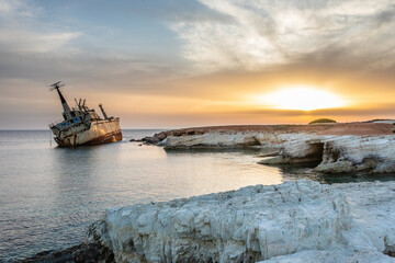 Obraz premium Abandoned rusty ship stranded ashore in the sunset rays at Peyia village, Paphos