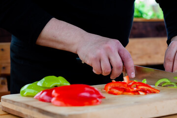 the cook cuts green peppers into strips on a wooden Board