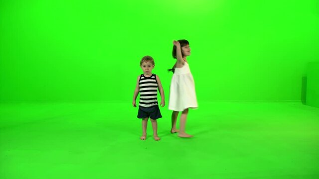 Two cute little kids dancing and playing around happily over green screen.