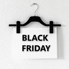Black Friday text on white paper hanging on clothespins on black clothes hanger on screw on grey...