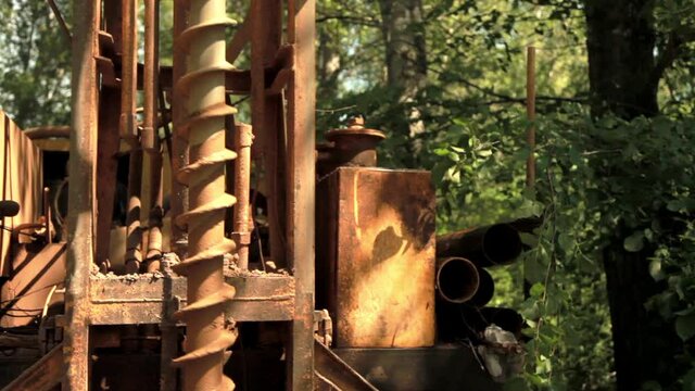 Water well drilling rig.Modern rotary drill rigs bore water well among green trees.